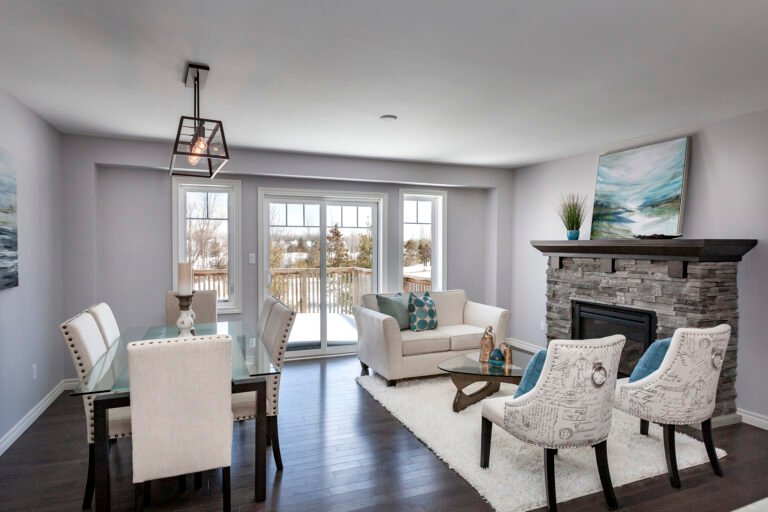 overview of a living room with white furniture, wood floors, a fireplace and a white rug