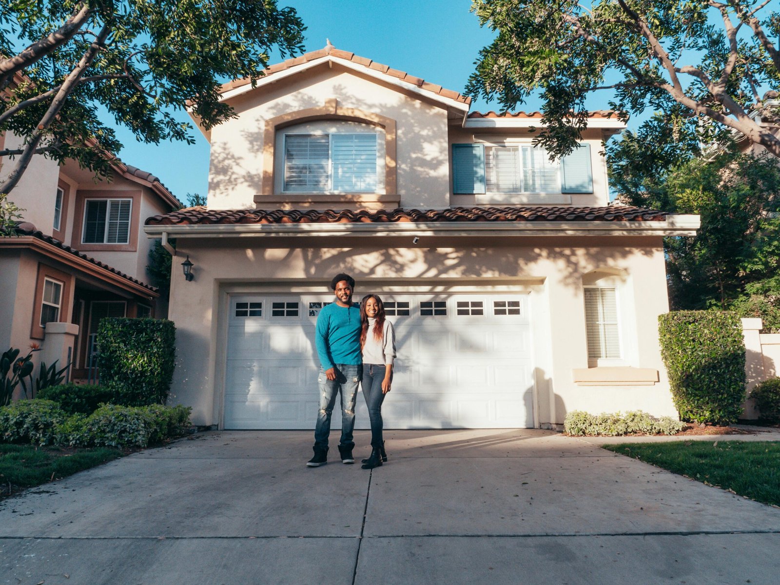 a couple standing in front of their home that they put on the market as for sale by owner