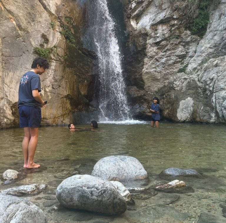 teenager standing atop rocks in front of Eaton Canyon Waterfall, located north of Arcadia