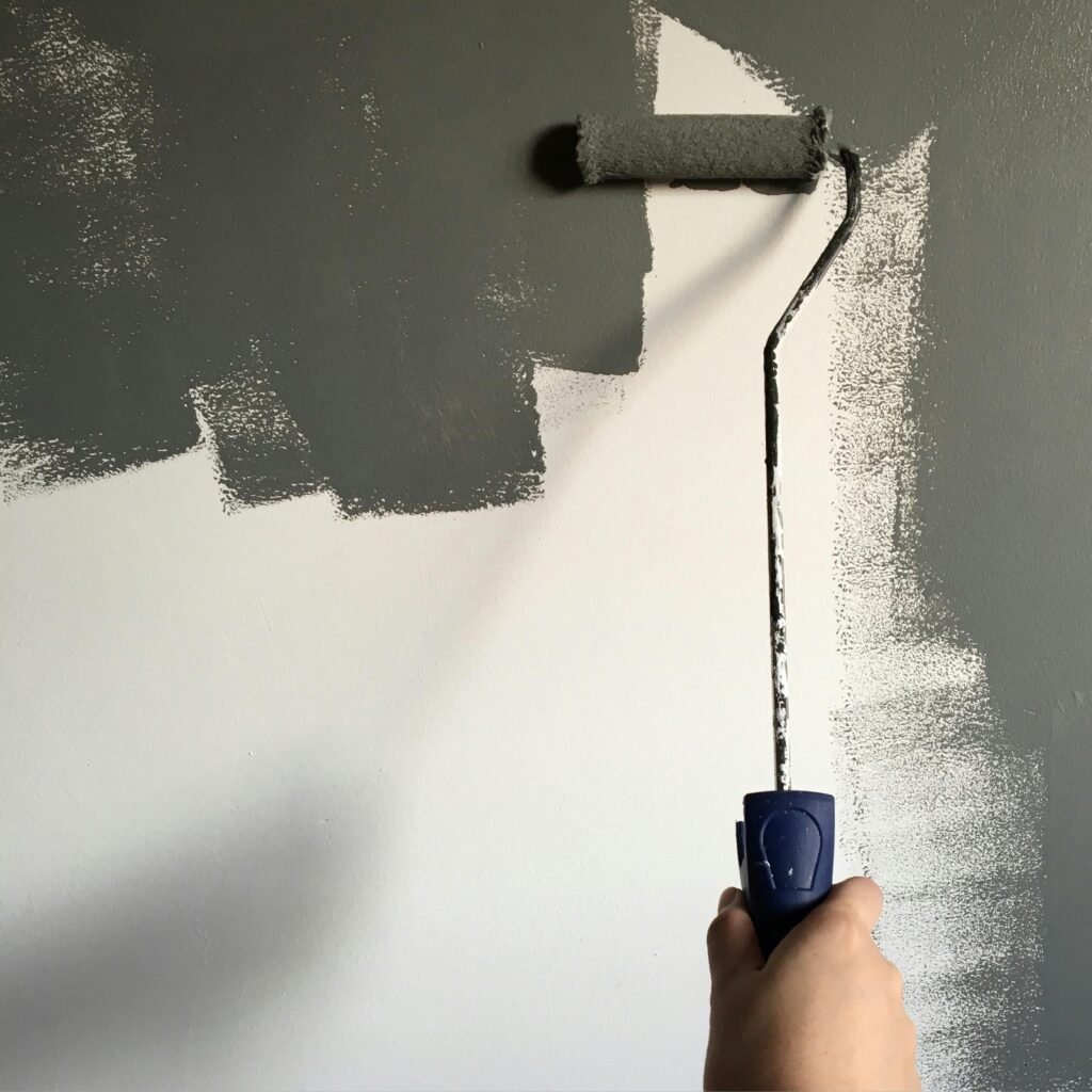 a view of a paint roller over a half painted white wall