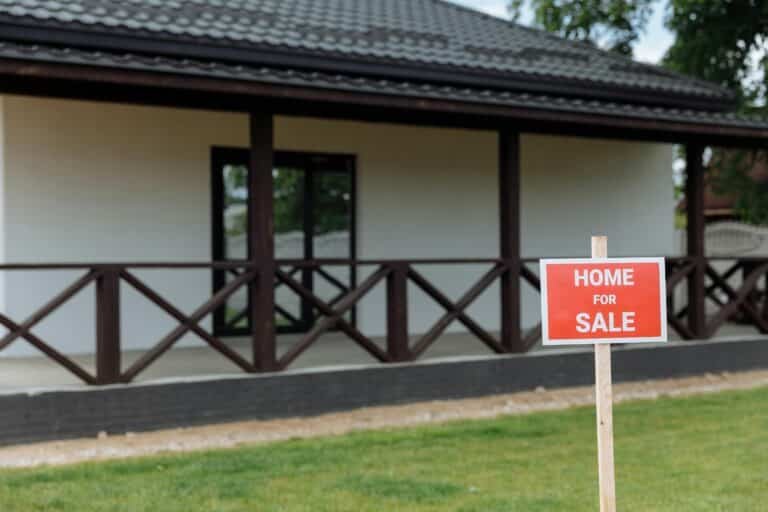 front lawn of a home with a picket for sale sign