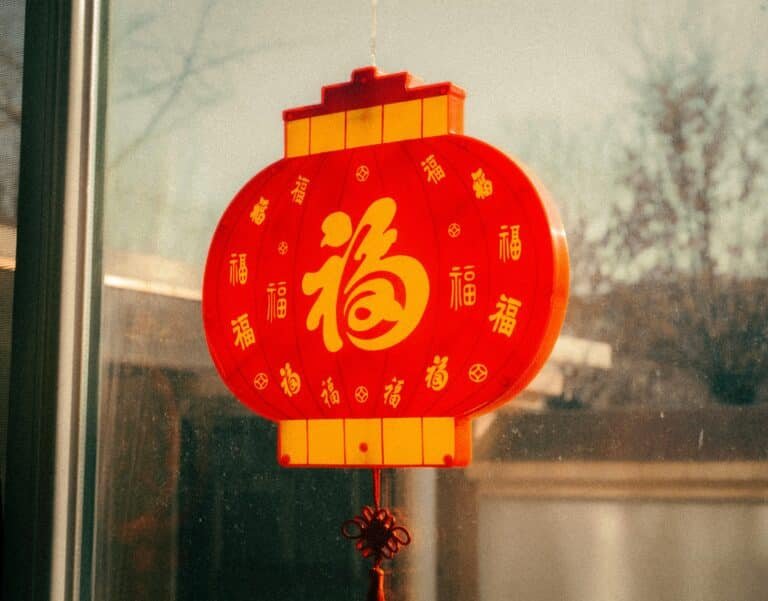 a traditional chinese paper lantern hung outside of a window, symbolizing the new year