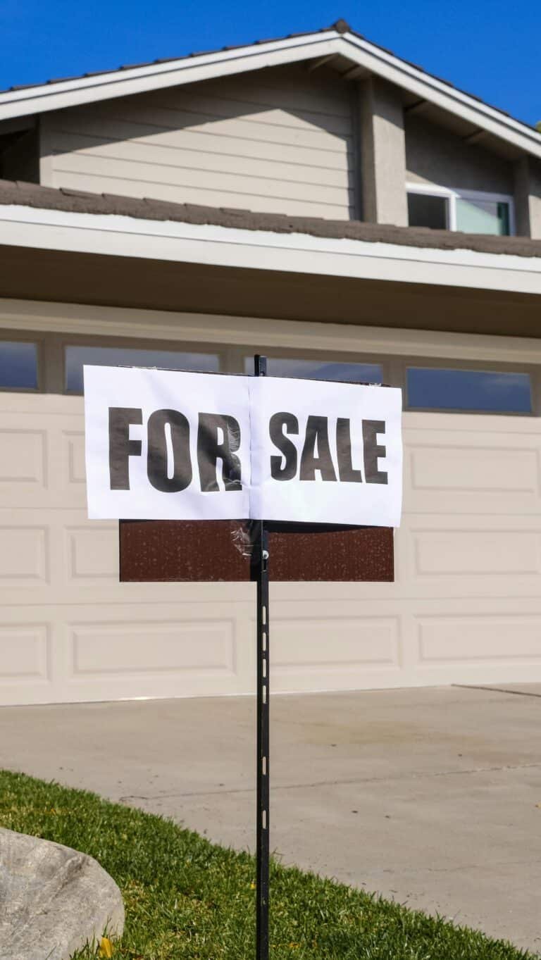 a small for sale sign propped up on the front lawn of a home